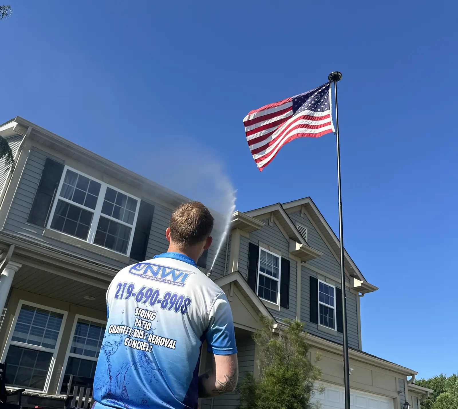 Alex pressure washing a house in Crown Point Indiana with American flag