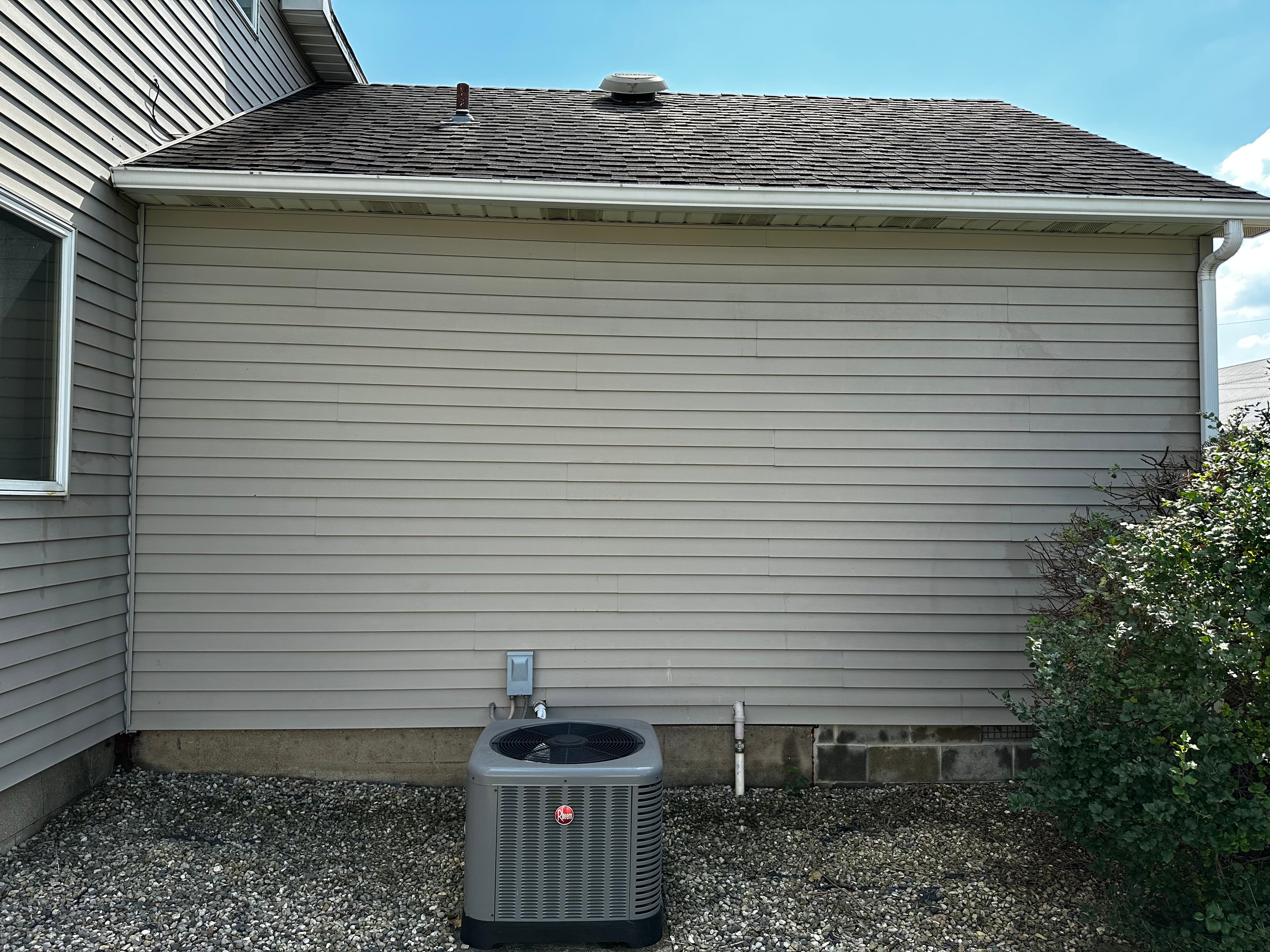 Back section of a Demotte house with clean siding and an HVAC unit post House Washing.