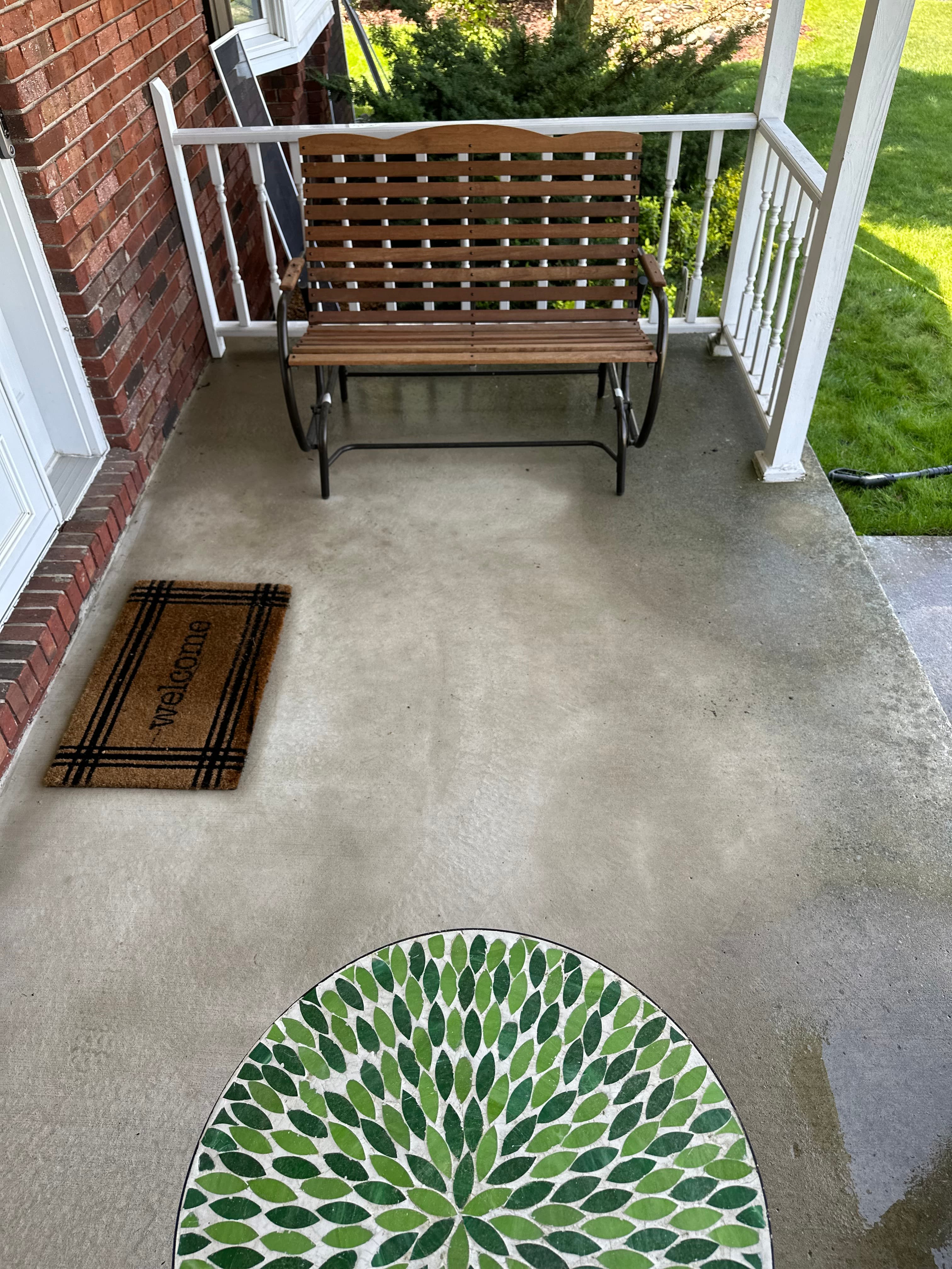 Freshly washed front porch in Valparaiso featuring a wooden bench and decorative mat on clean concrete.