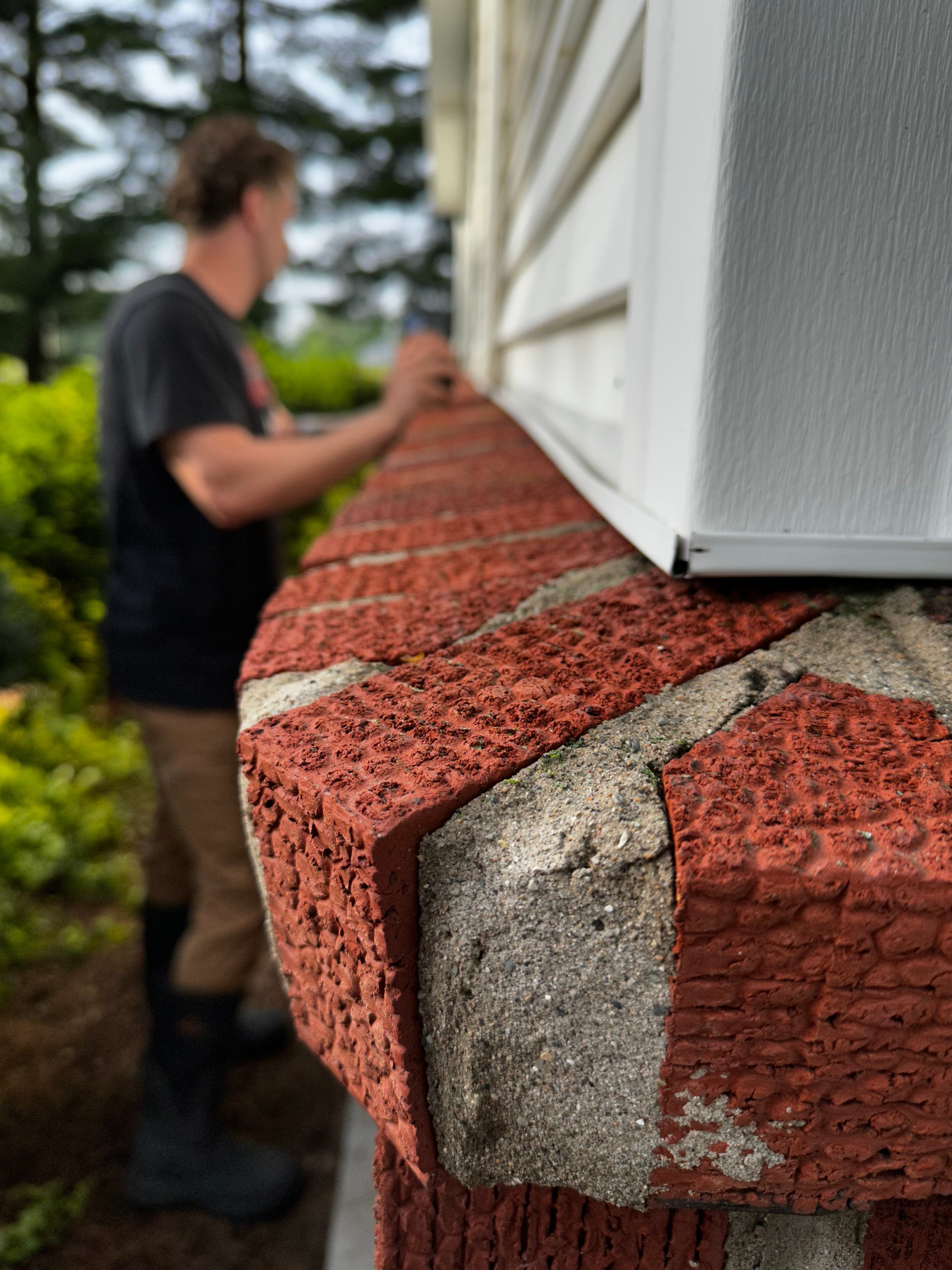 Man inspecting clean brick ledge after house washing in Wheatfield, Indiana, showing sharp, clean edges.