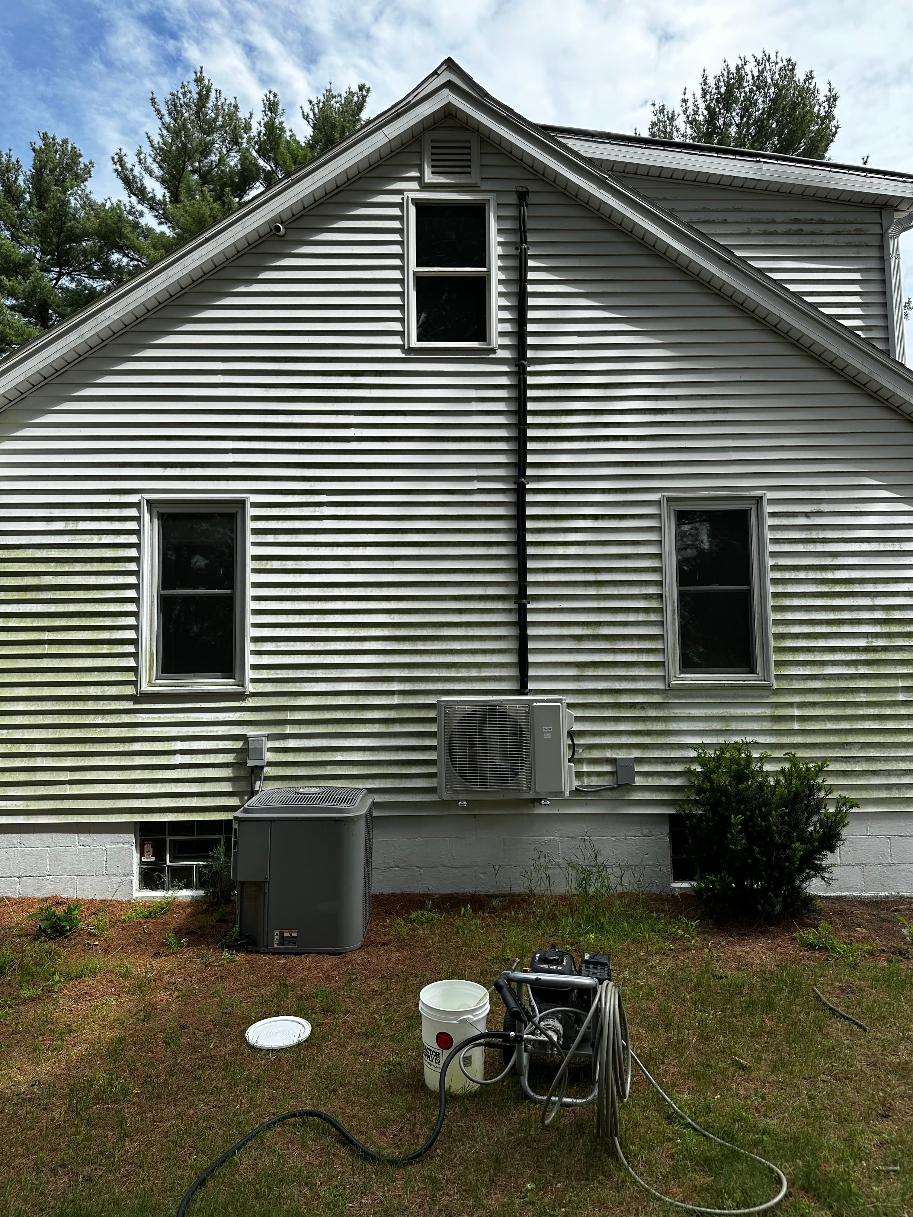 Dirty white siding with green algae stains before house washing in Wheatfield, Indiana, indicating extensive surface grime.