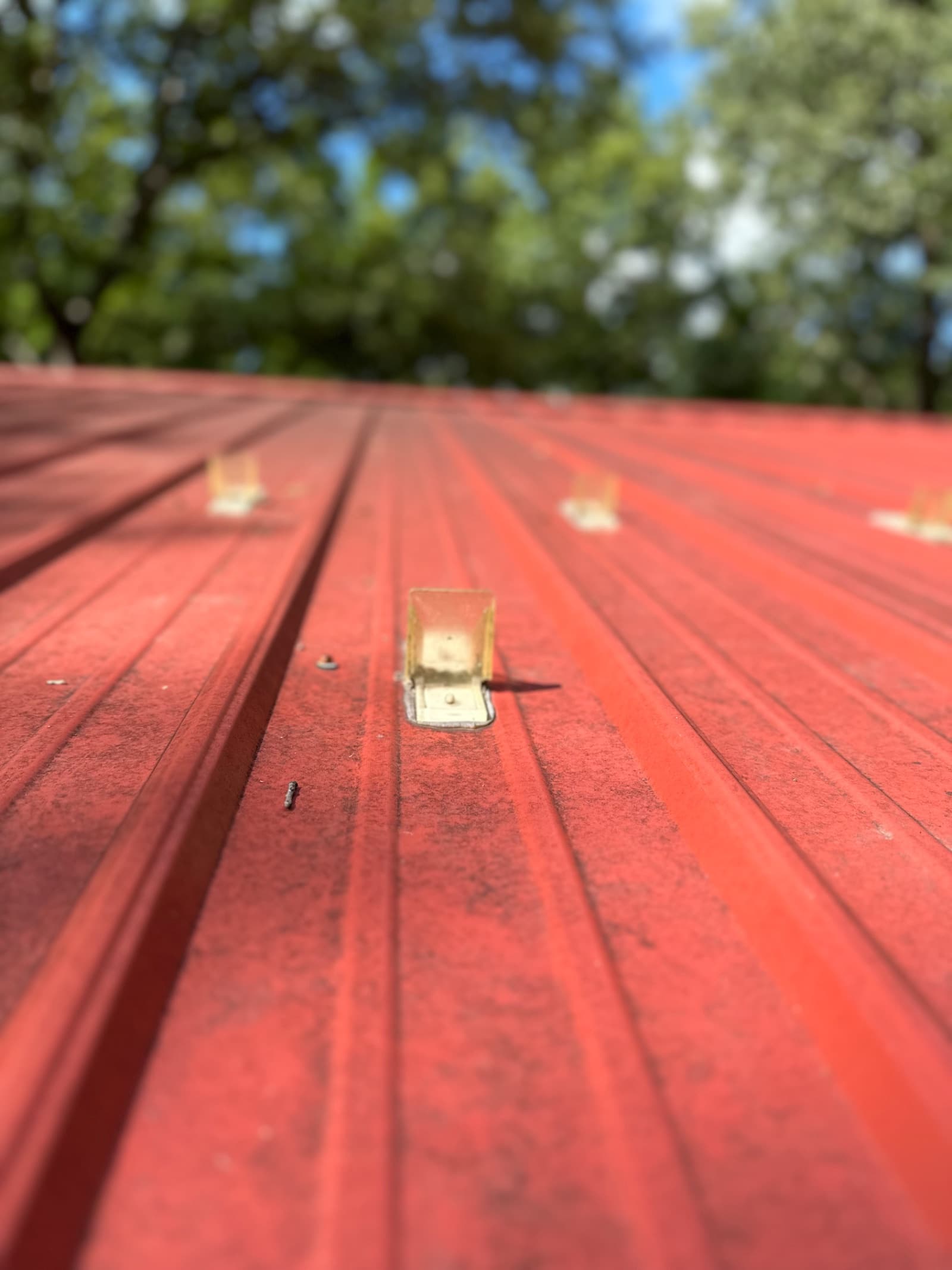Red metal roof with light dirt and debris before cleaning in Lowell, Indiana.