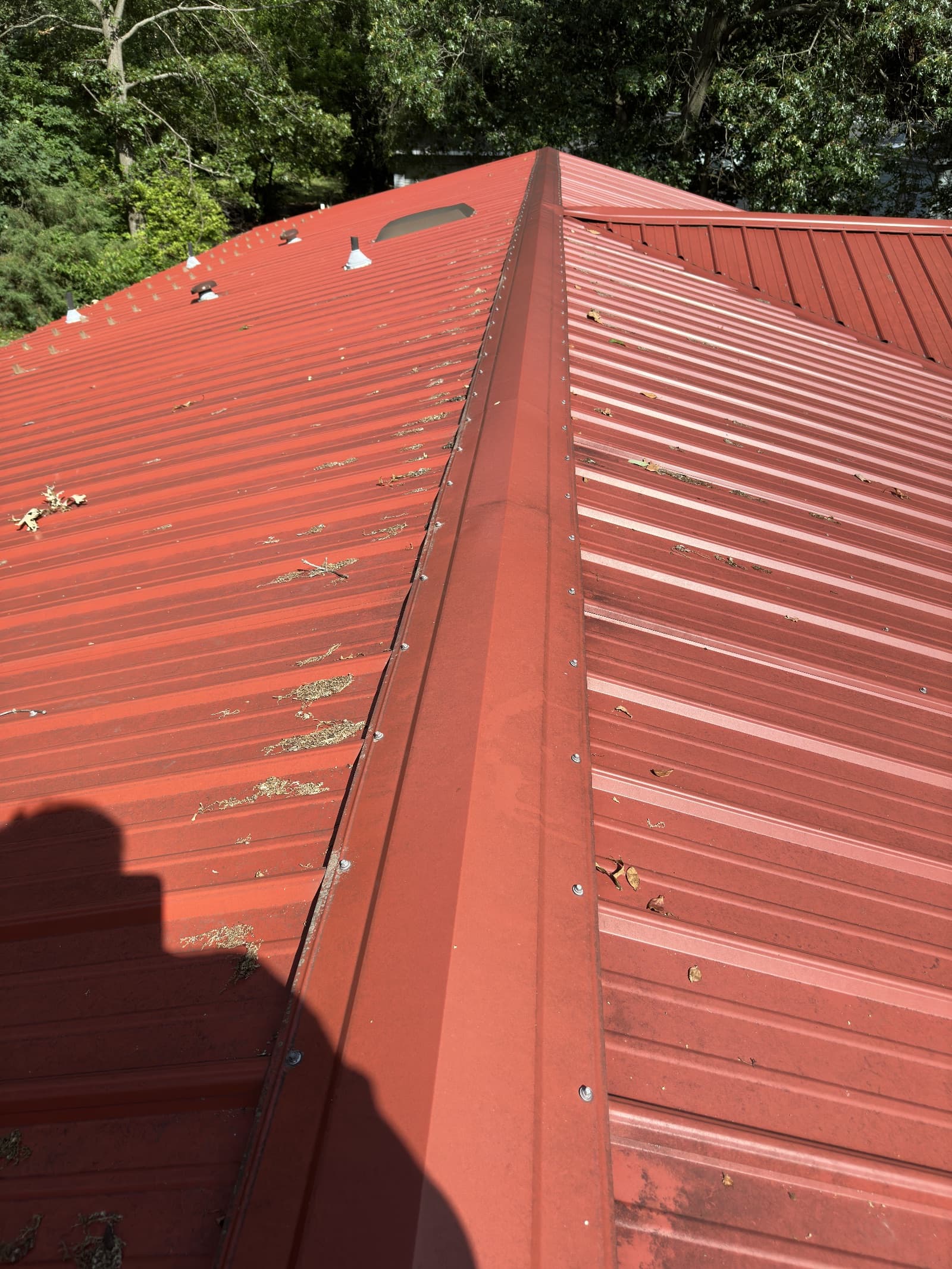 Red metal roof with dirt and debris before cleaning in Lowell, Indiana.