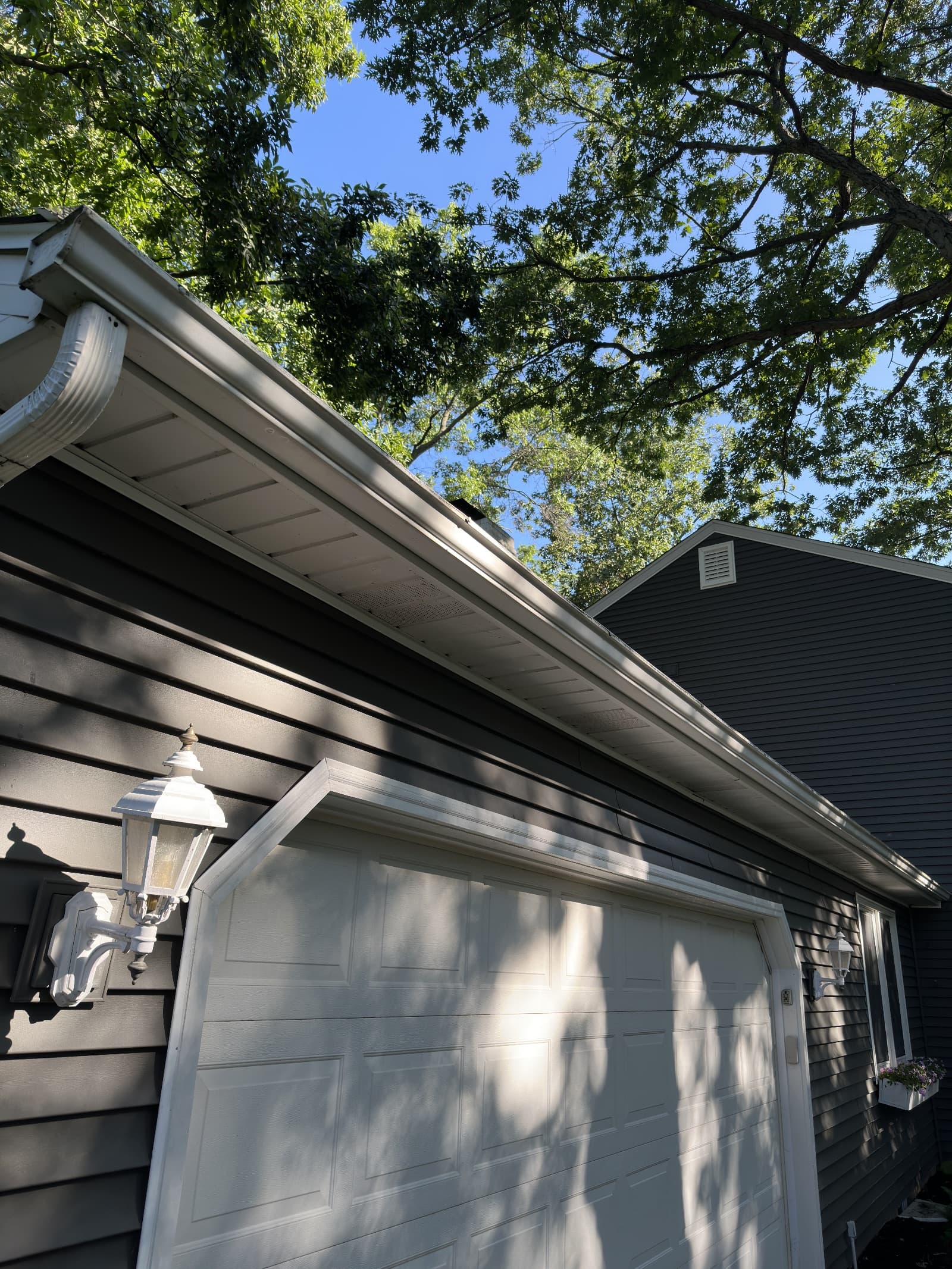 Clean dark vinyl siding and white garage in sunlight