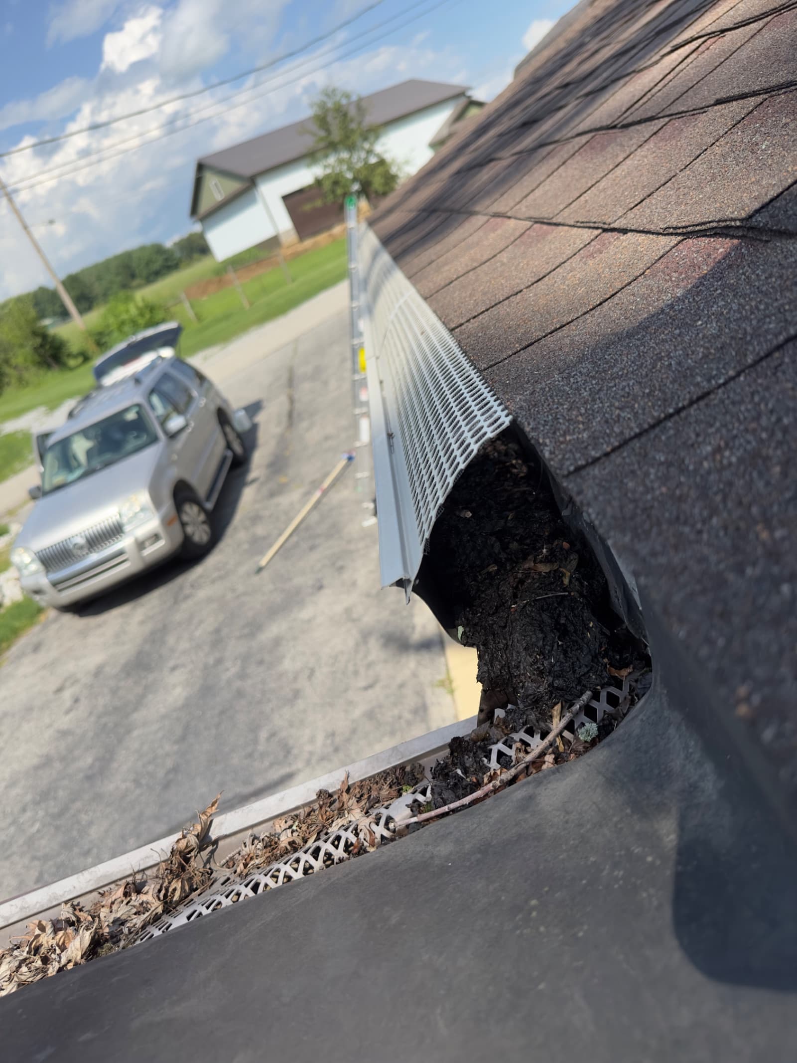 Clogged gutter with debris and installed guard in Rensselaer, Indiana.