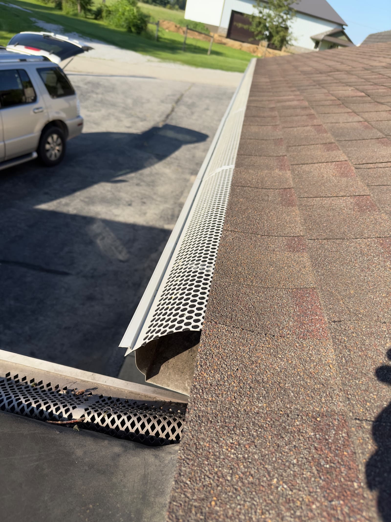 Clean gutter with guard installed on shingled roof