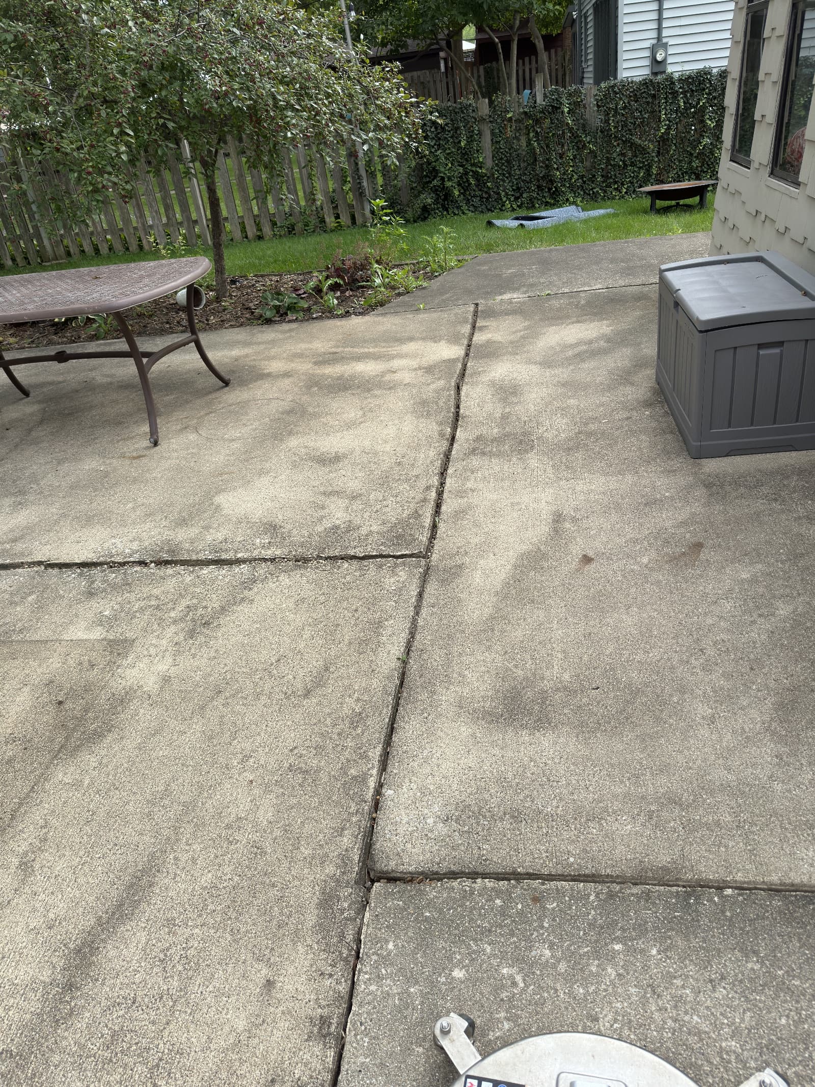 Concrete patio with visible dirt and stains before cleaning in Crown Point, Indiana.