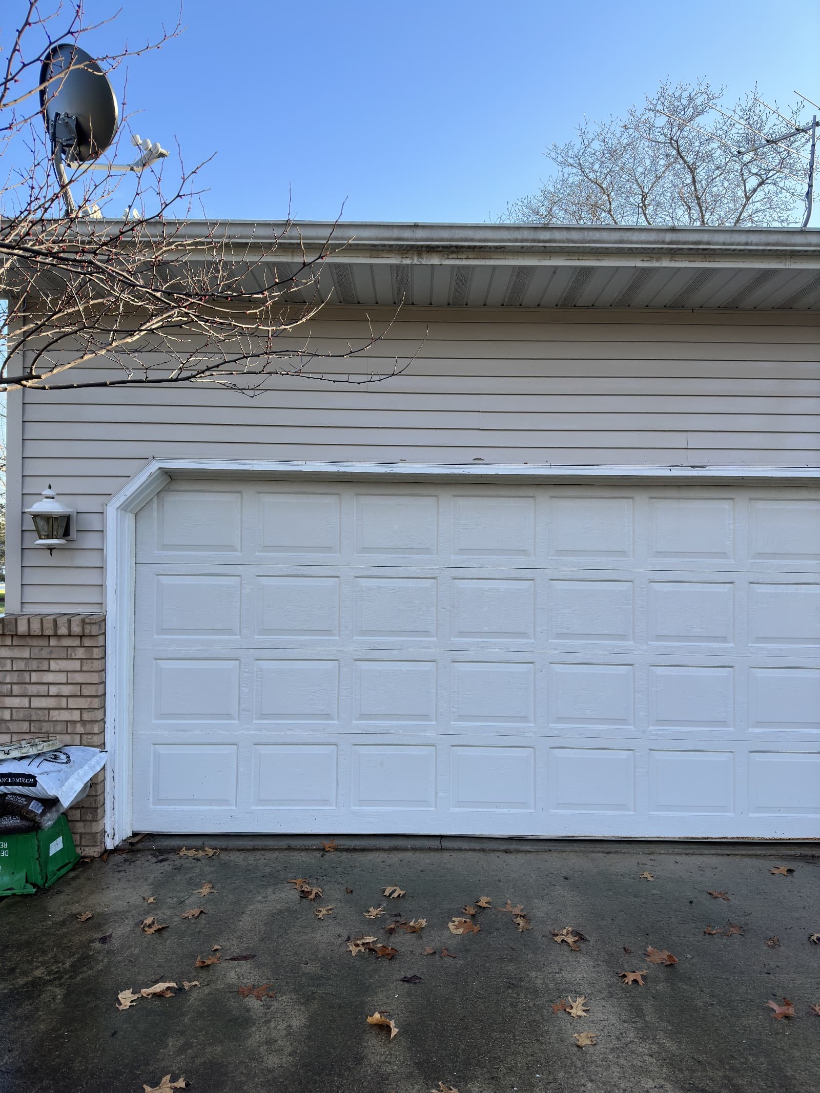 Garage door and driveway with leaves and light dirt in Wheatfield, Indiana.