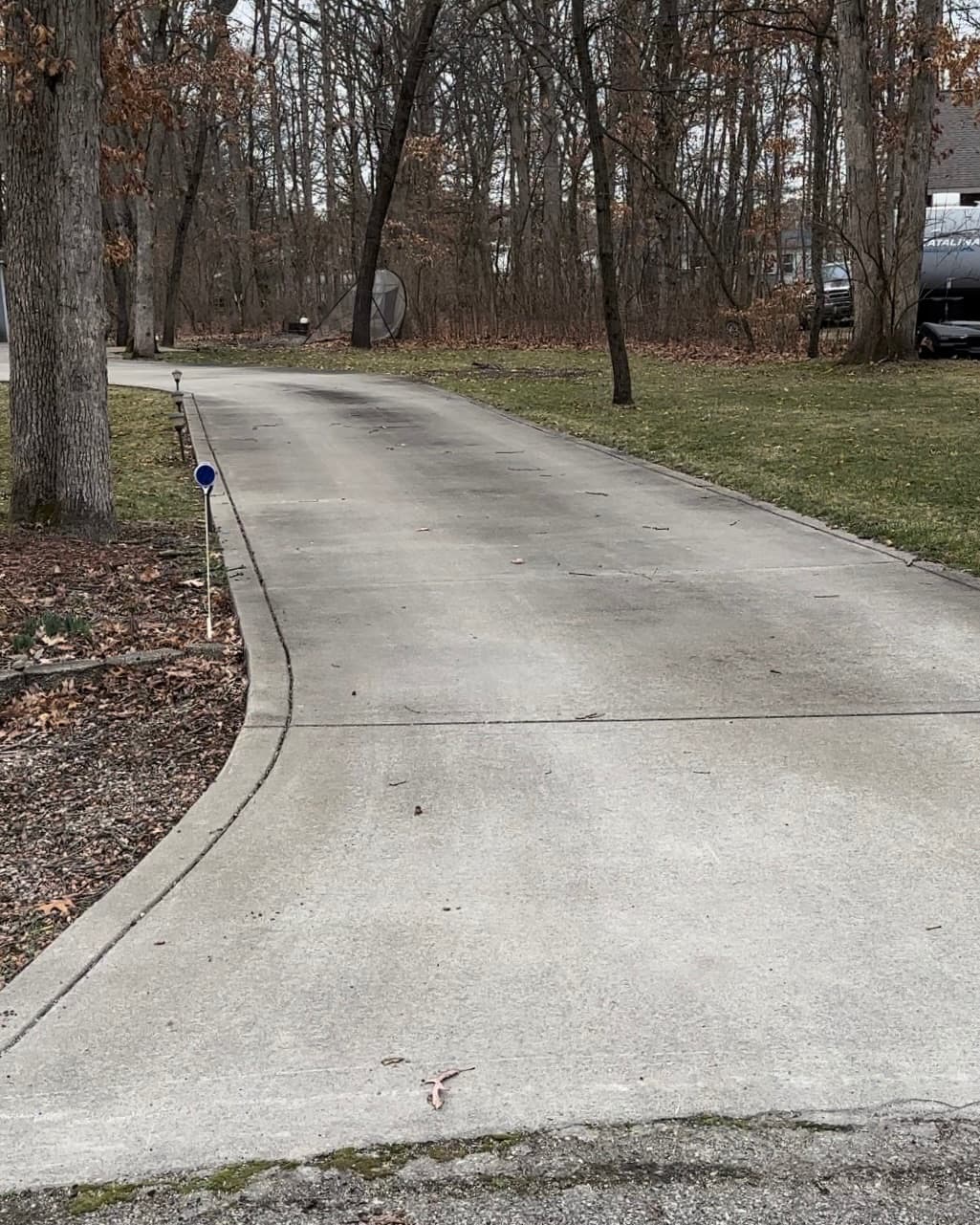 Clean concrete driveway surrounded by trees in Demotte, Indiana.