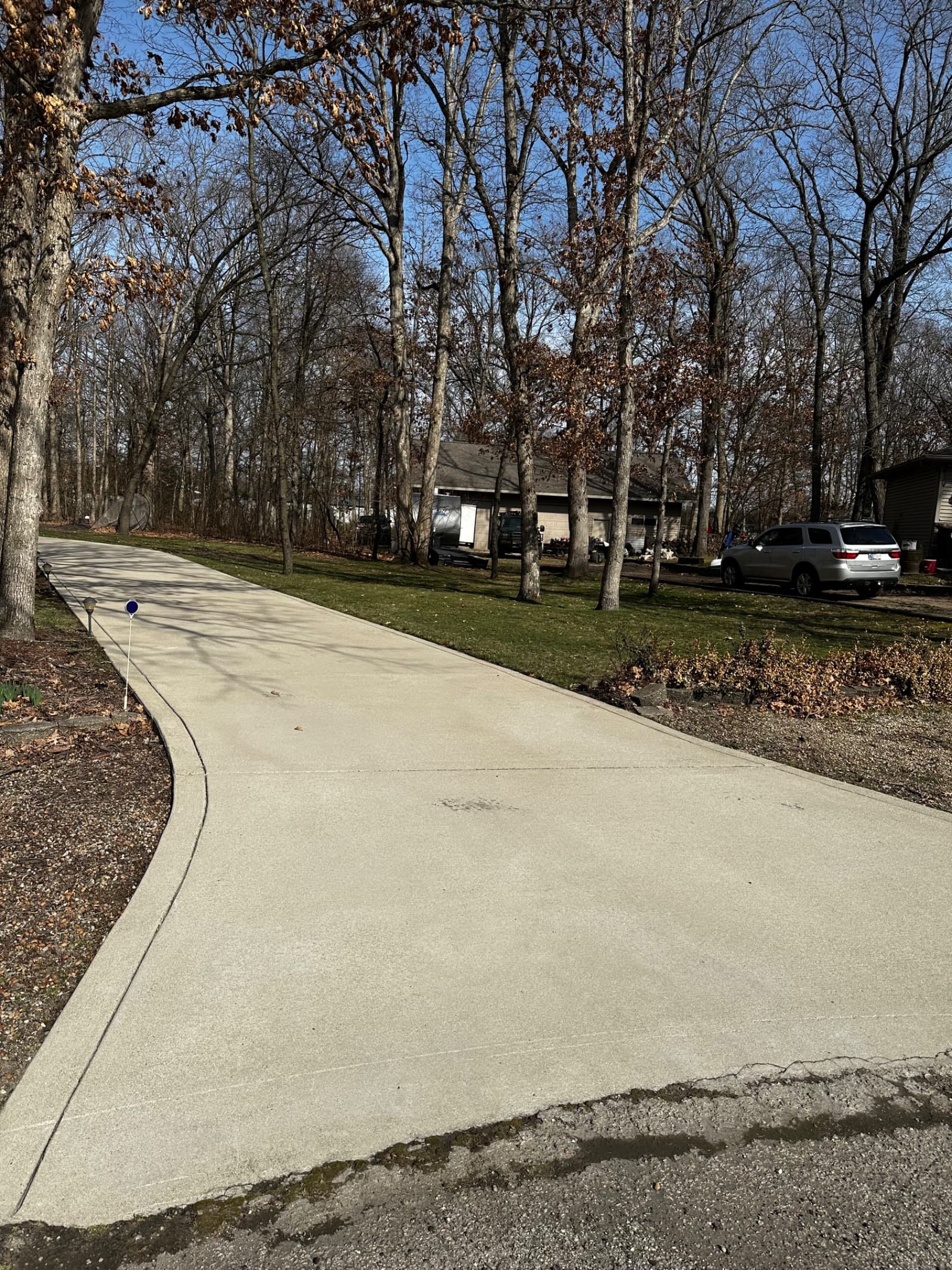 Clean concrete driveway surrounded by trees in Demotte, Indiana.