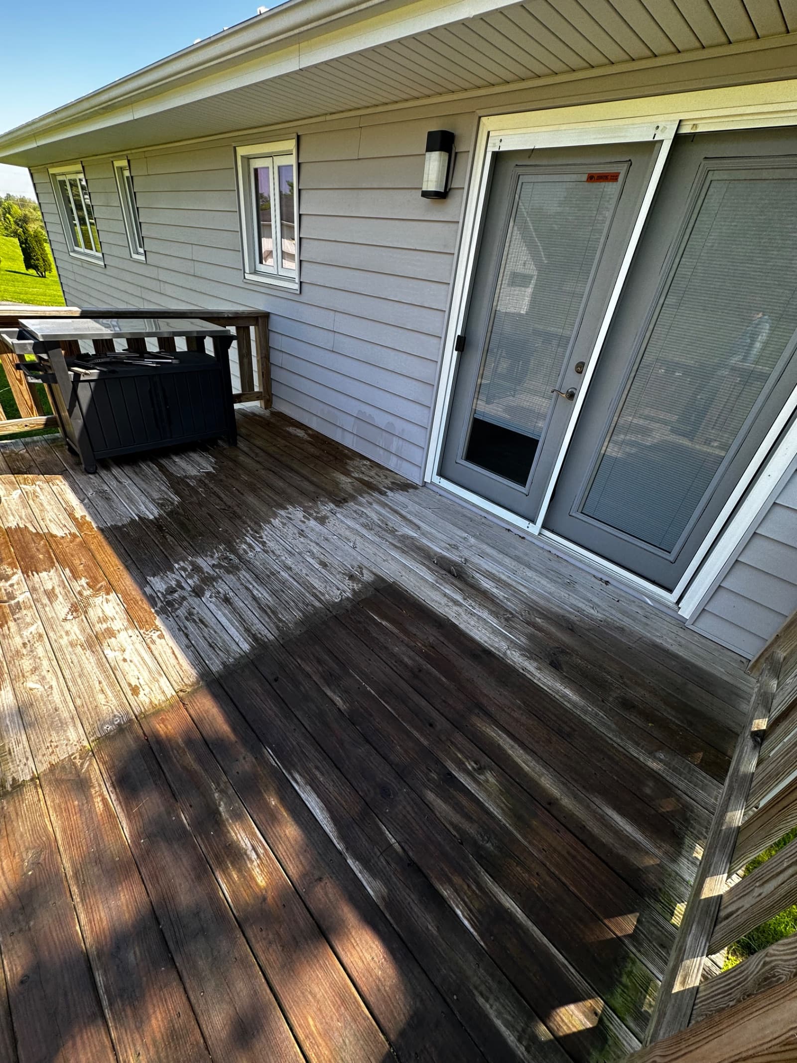 Partially cleaned wooden deck with visible dirt and stains